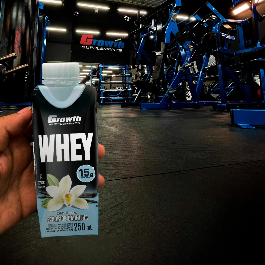 Uma mão segurando a bebida Bebida láctea uht de proteínas - growth supplements no fundo de uma academia